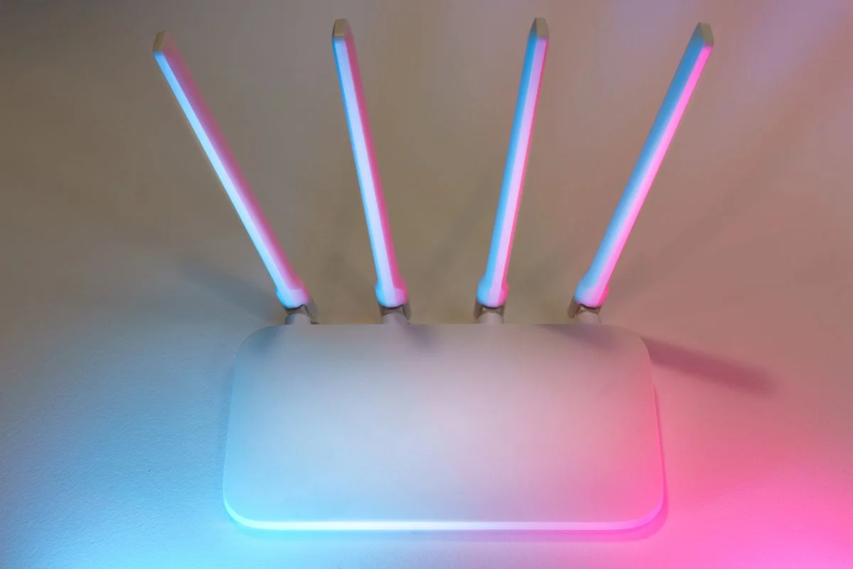 Roteador Wi-Fi branco com antenas iluminado, representando a rede doméstica usada por comedouros conectados